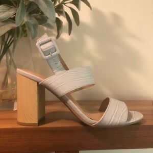 Sandal buckles for a secure fit with a block heel, a padded footbed.